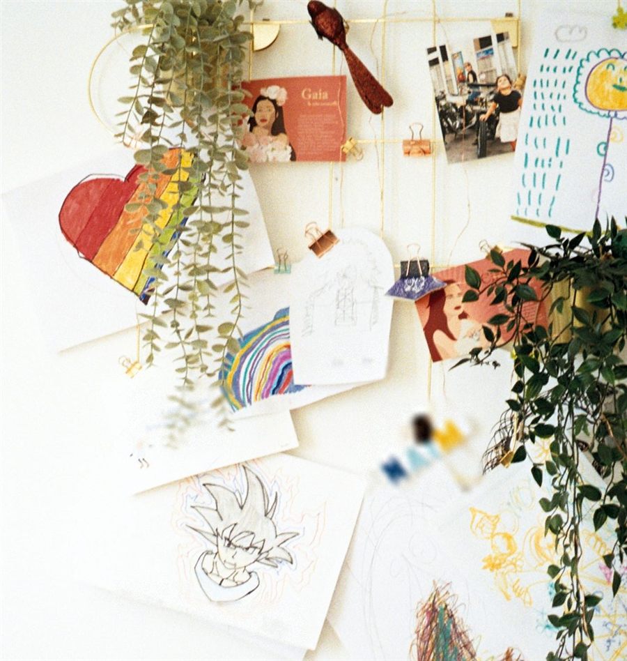 Un mur du cabinet couvert de dessins d'enfants, de cartes illustrées et de plantes.